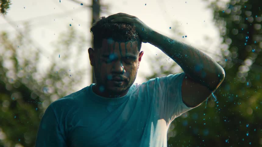 Portrait of a man with closed eyes taking a shower in blue paint rain