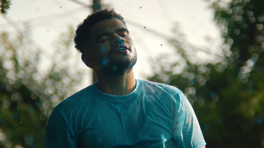 Drops of blue paint wetting a man outdoors
