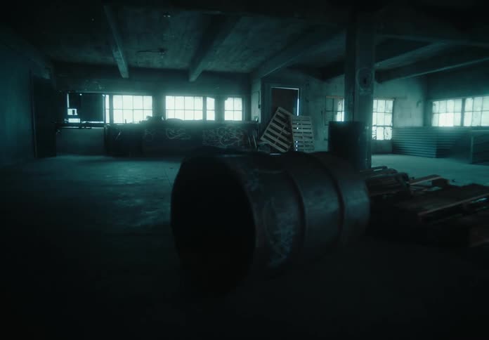 A dusty and abandoned room with a barrel and wooden pallets scattered around
