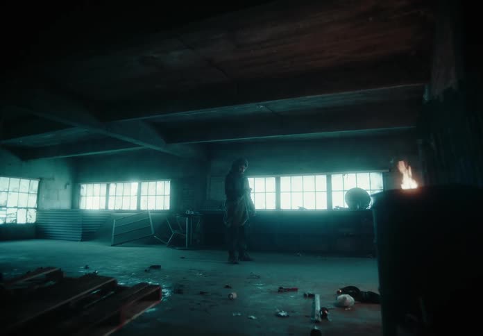 A person stands in a dimly lit room with scattered debris