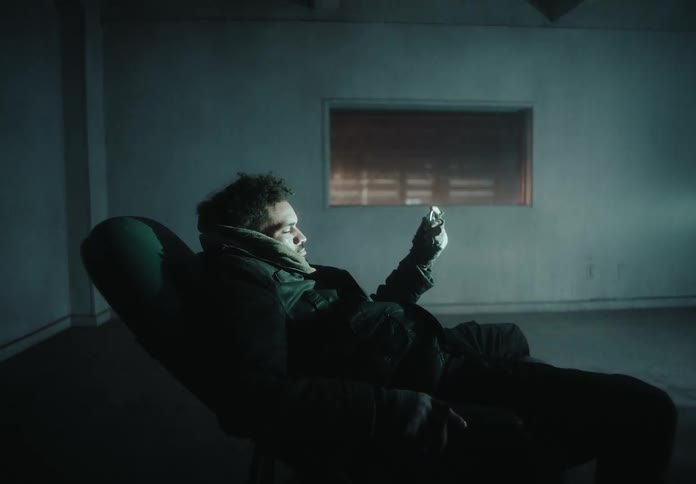 A person is reclining in a dark room holding a ring in front of a flickering light