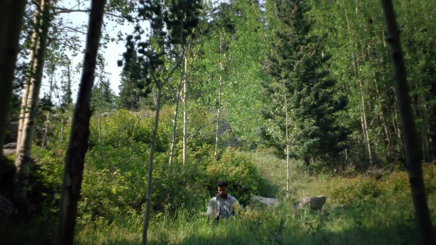 A man sitting and meditating in a forest