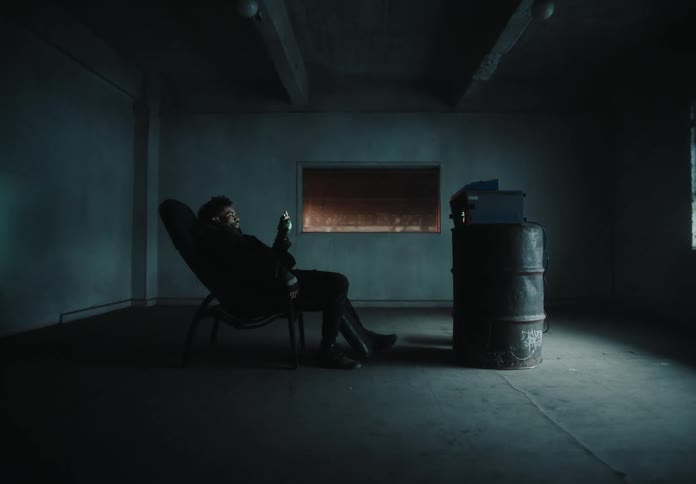 Man sitting in an armchair observing an object in his hands inside an empty room in winter