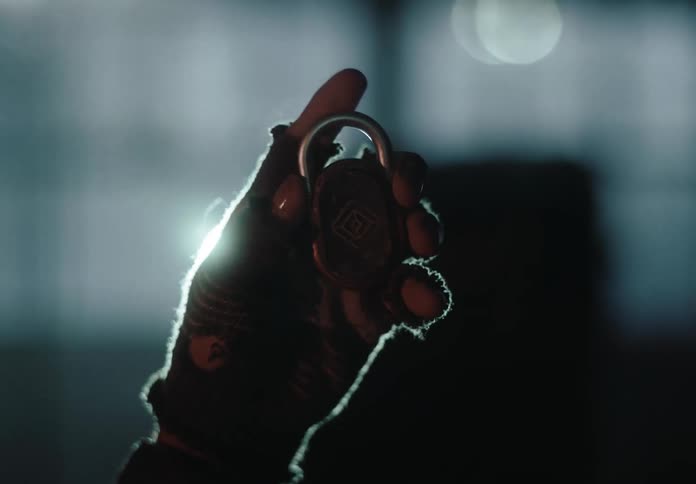 A person holding on to a padlock in a dark place with a bright light shining