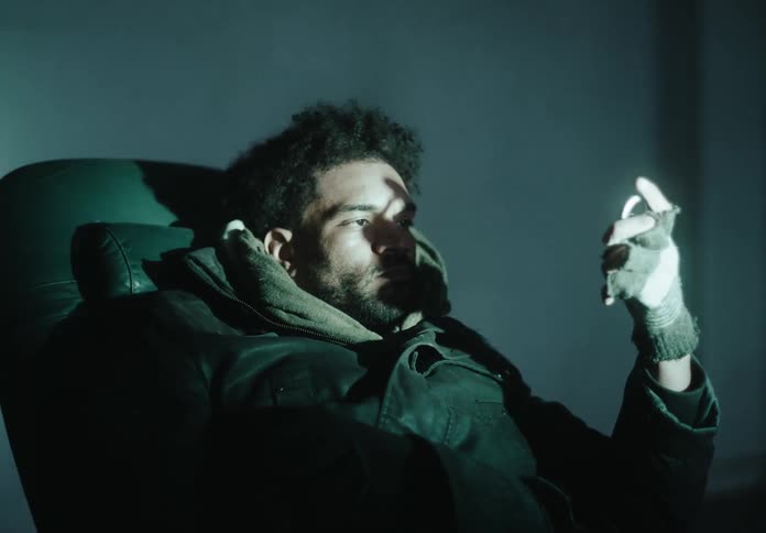 Man sitting in armchair and looking at an object in his hand and becoming hypnotized