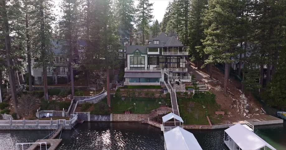 Aerial view of modern lake house with lots of windows overlooking the docks with the sun rising in the background