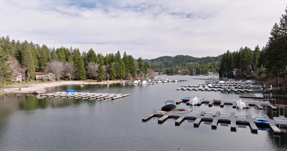 A lake with calm waters and cloudy sky with many boats moored along wooden docks