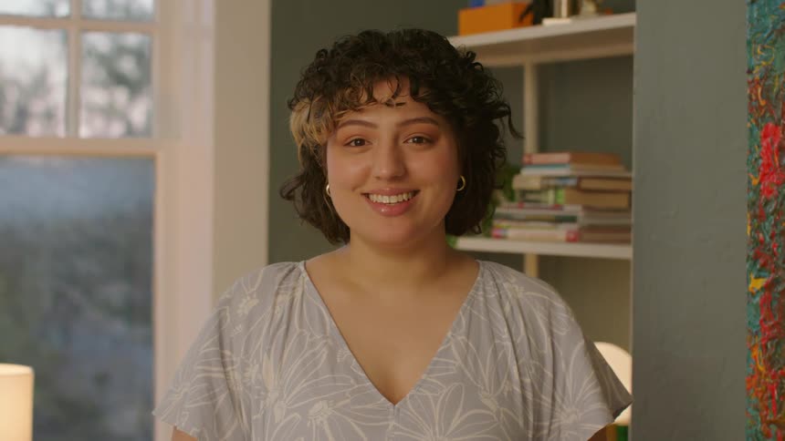 A woman with curly hair smiling in a room