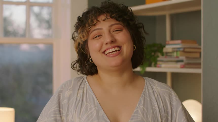 A happy young woman smiles and laughs at the camera