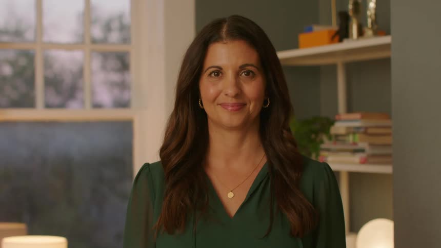 Woman with long hair and green blouse looks at the camera