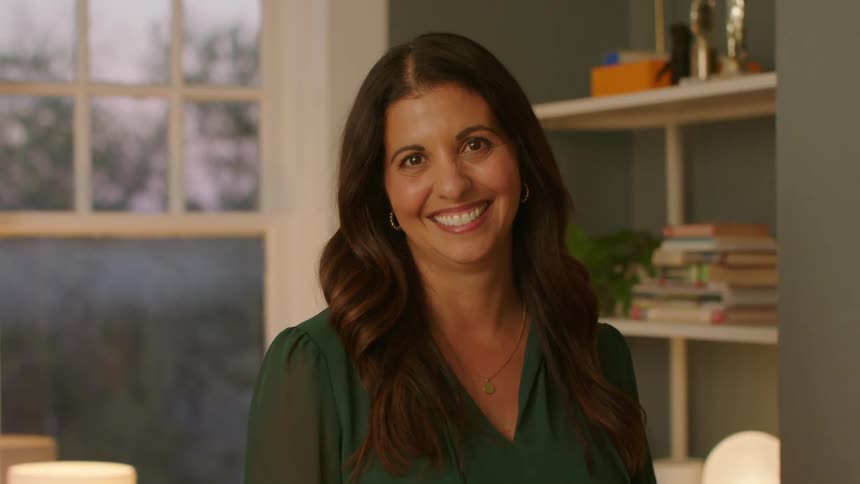 A woman smiling in a room at sunset