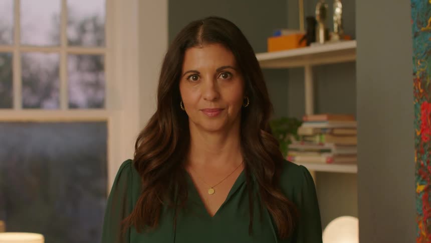 Woman with long hair and green blouse looks at the camera