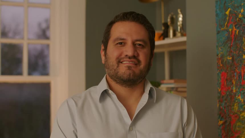 A smiling man next to a painting