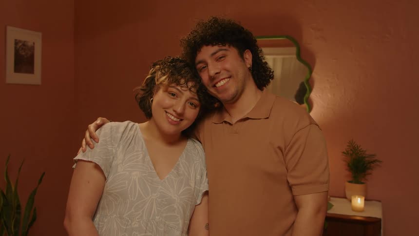 Man and woman smiling while hugging in a room