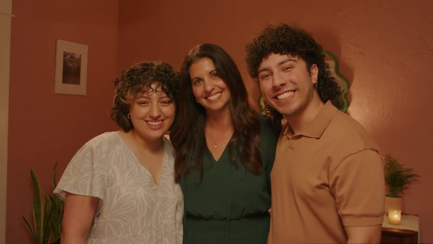 A clip of a male and two females posing and smiling for a photograph