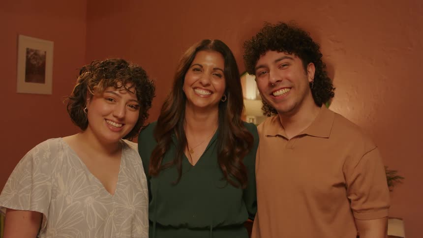 Three people stand in a room together smiling