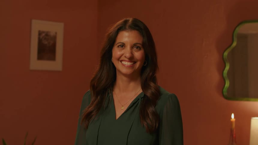 Happy woman with long hair smiles at the camera in a cozy room