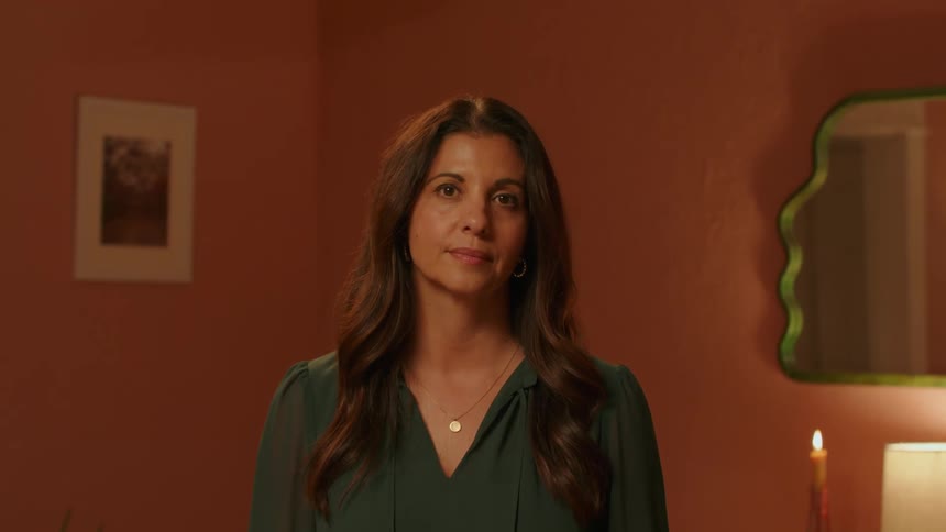 Woman with long hair and a green blouse looks at the camera