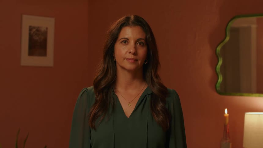 Woman with long hair and green blouse looking at the camera
