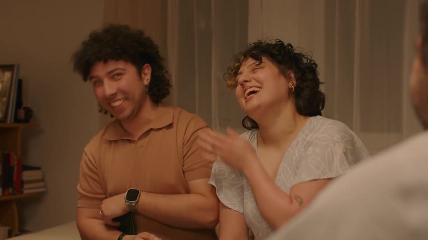 A man embarrassed by family photos closes the album and laughs with his girlfriend