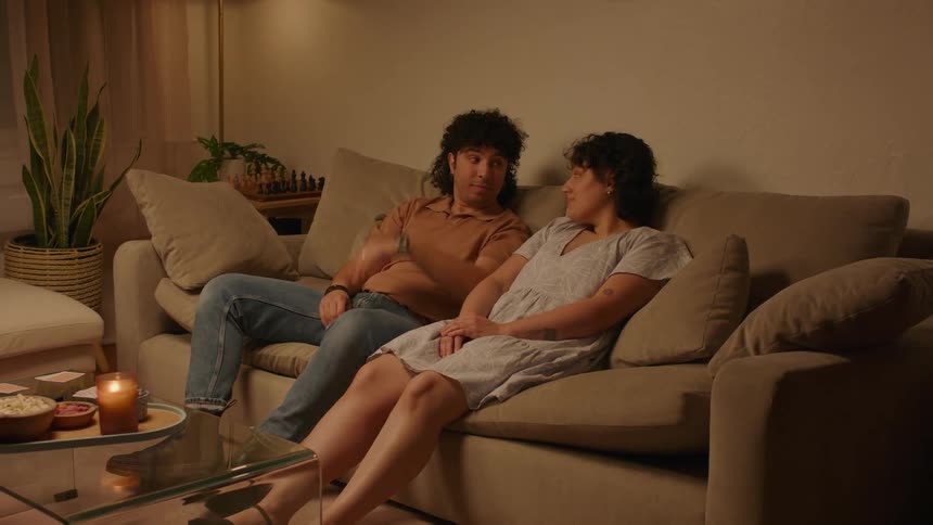 A man and a woman sit together on a sofa and then hug each other