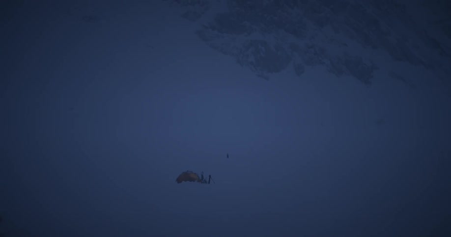 Aerial panorama of a tent amidst an icy mountain at night