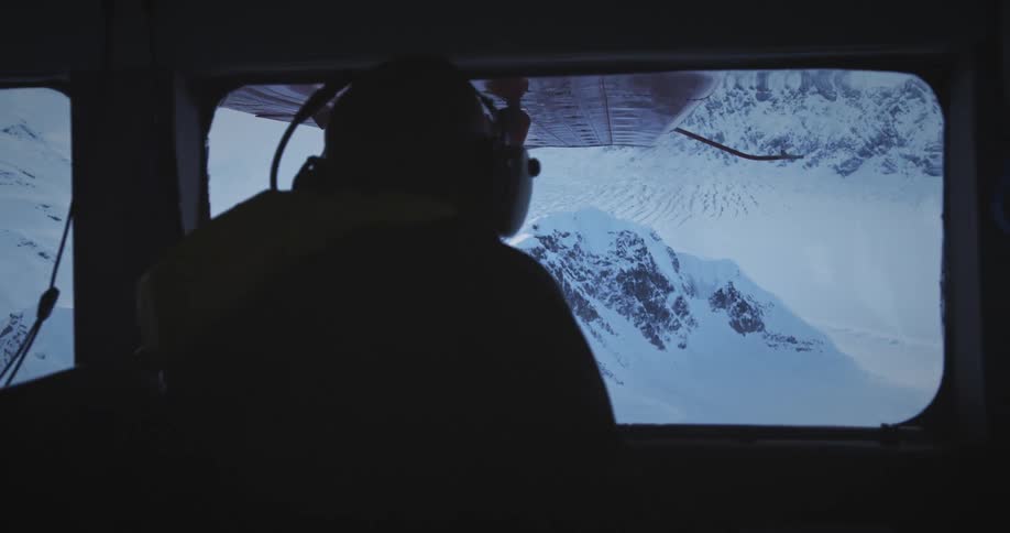 A man is flying his plane over the mountains