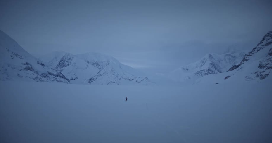 A person walking alone across a large valley covered in snow