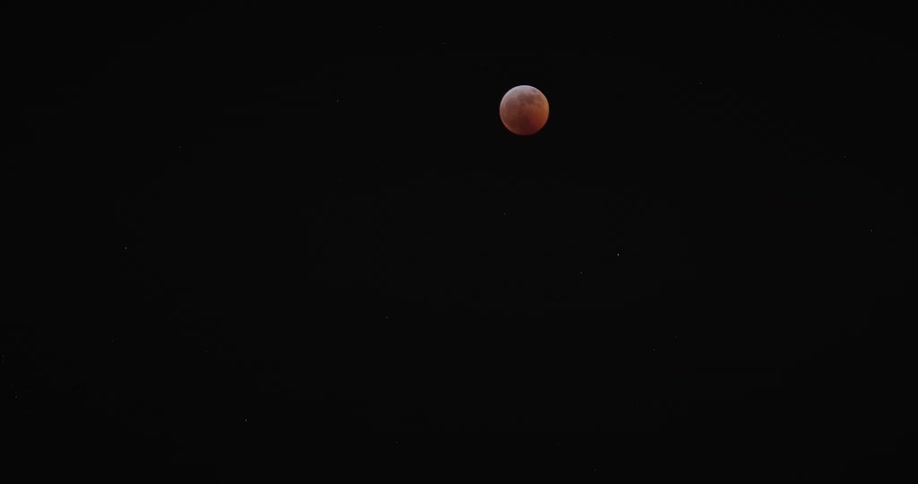 The moon is red in the clear night sky
