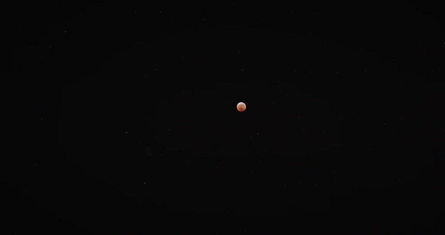 A dimly lit full moon hanging in a dark sky at night
