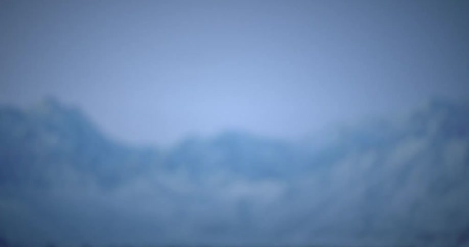 Drone rising in the middle of a natural environment with a snowcovered mountain range on the horizon