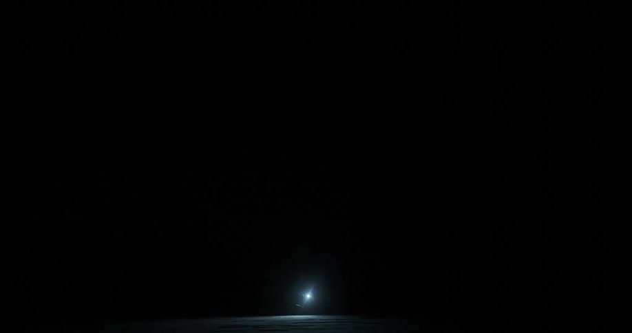 Flashlight illuminating a snowy ground while its snowing