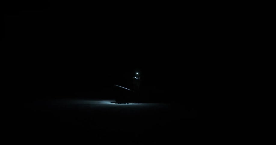 A person in protective clothing with a flashlight during dark night