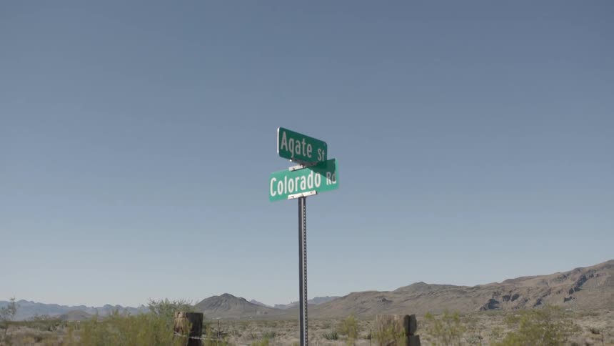 A street sign in the desert is blowing in the wind