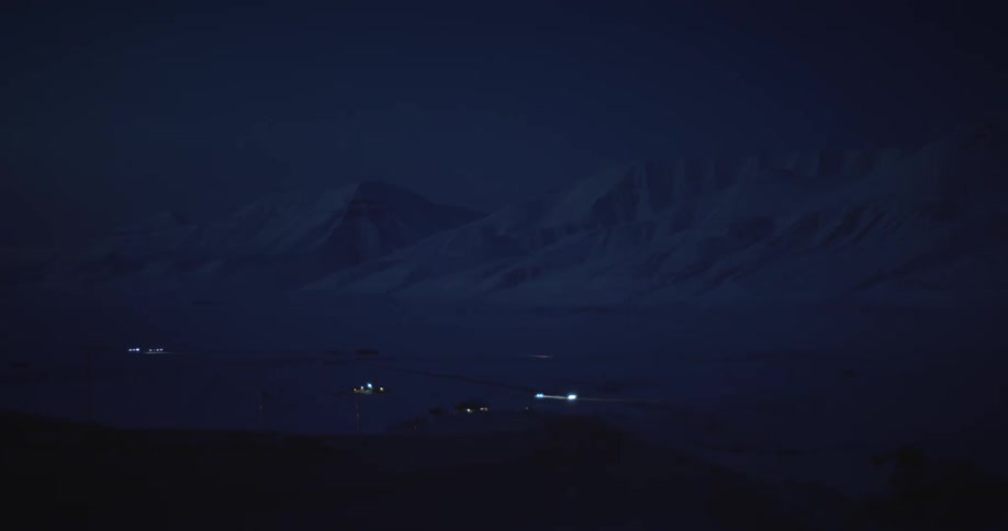 Cars driving up a winding road with a snowcovered mountain range in the back