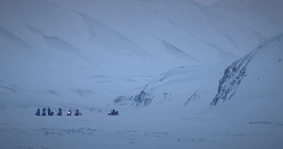 A group of people riding snowmobiles across the frozen mountain