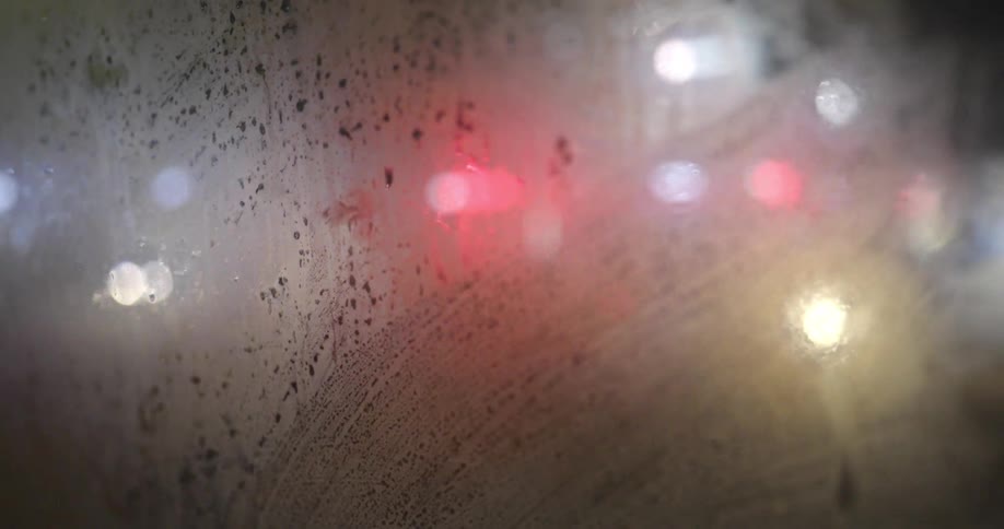 Car headlights and streetlights seen through a fogged up glass