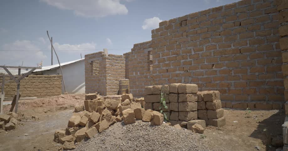 An uncompleted building in a village without a roof with blocks lying beside it