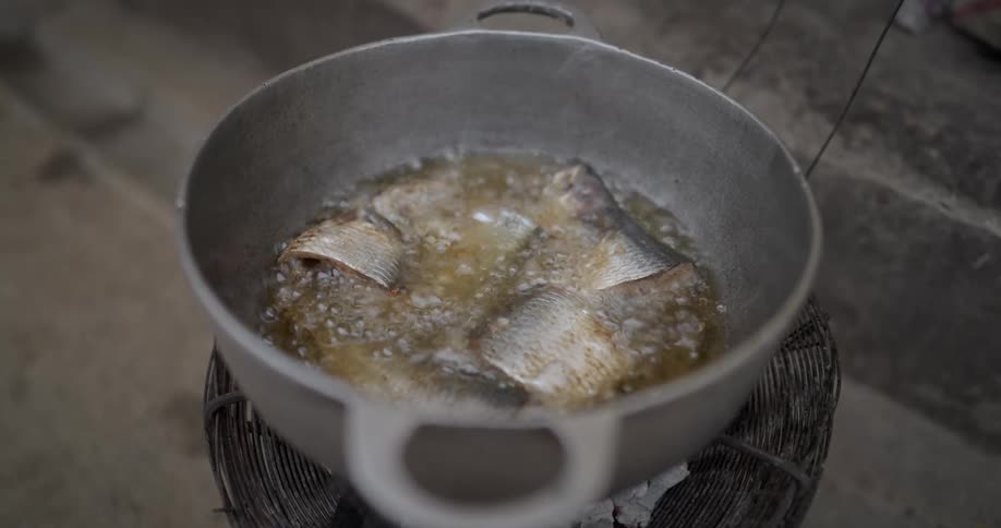 Fish frying on a pot outdoors