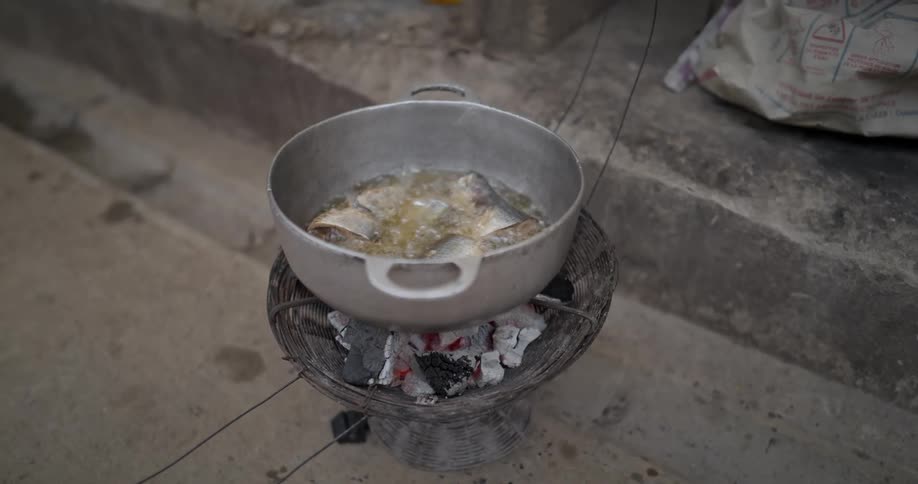 Fish frying in oil inside a pot outdoors