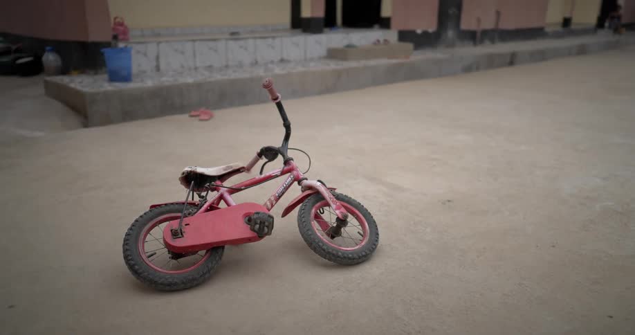 Childs bicycle lying on the ground in a concrete backyard