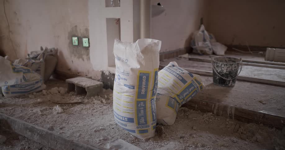 Two bags of concrete are in the messy room
