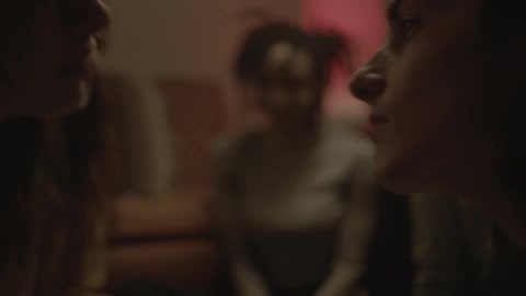 Two people in a home kissing while other people watch