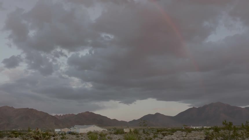 Large storm clouds gather in the sky above mountains