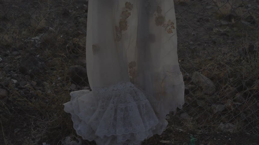 A person wearing a white dress stands in the grass