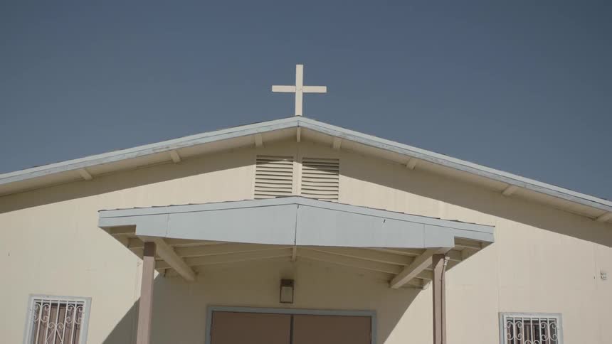 The outside entrance to a church, focusing on the cross above the door