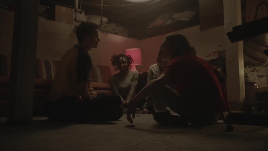 Group of people playing spin the bottle in a dimly lit room