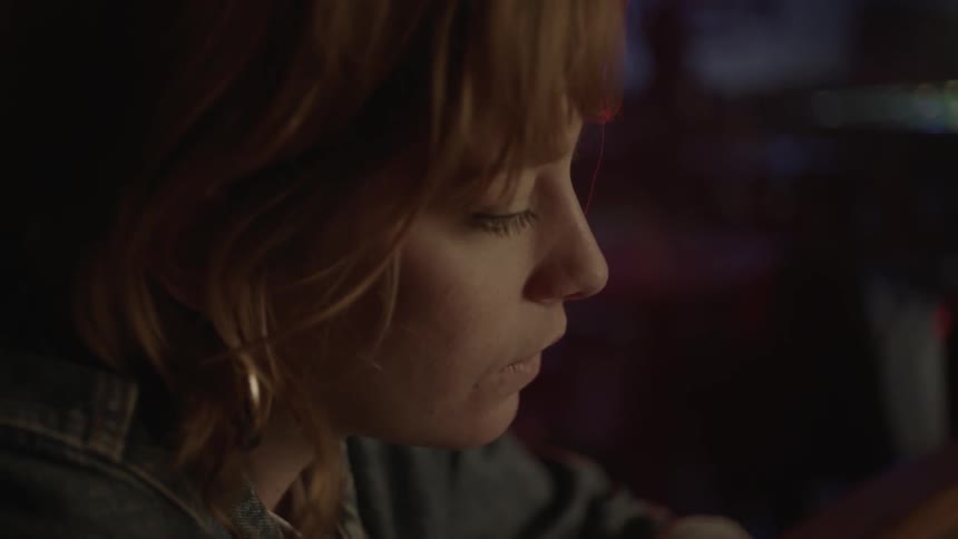 A woman looks to her side and speaks