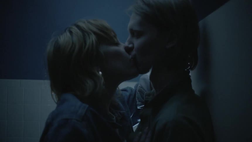 A couple of people kissing in a room with a flashing light