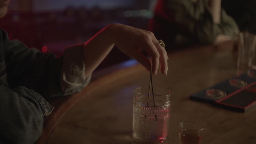 Woman plays with the straws in her drink at a bar